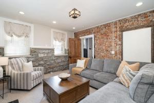a living room with a gray couch and a brick wall at Rutledge After Dark - Walk to Broadway & The Gulch in Nashville +67 photos