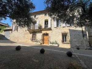 a stone building with a brown door and black balls on the street at Le patio de Collias in Collias
