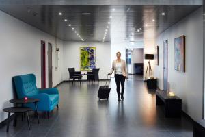 a woman walking down a hallway with a suitcase at Cabinn Aarhus in Aarhus
