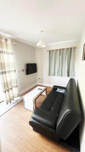 a living room with a black leather couch and a tv at The Apple House in York