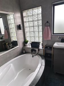 a bathroom with a large white tub and a sink at Protea House - self-catering house with a Pool in Durban +6 photos
