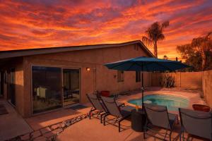 a patio with chairs and an umbrella and a pool at Cactus Spur - Pool & Fire Pit - Mins to Old Town in Scottsdale