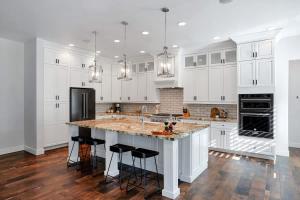 a kitchen with white cabinets and a large island with bar stools at Contour - Sparkling Pool - Mins to Phoenician Golf in Phoenix