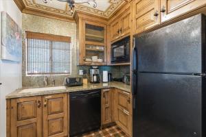 a kitchen with a black refrigerator and wooden cabinets at Rhone - In Old Town - Walk to Fashion Square in Scottsdale