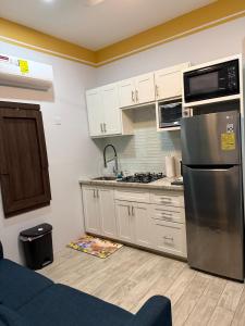 a kitchen with white cabinets and a stainless steel refrigerator at Charm New Kingston in Kingston