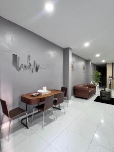 a dining room with a table and chairs and a couch at Cozy Clover house in Hat Yai