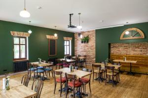 a restaurant with wooden tables and chairs and green walls at Willa Bywaj Zdrój in Lądek-Zdrój