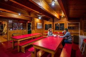 two people sitting at tables in a room with red tables at HI Kananaskis Wilderness - Hostel in Kananaskis Village
