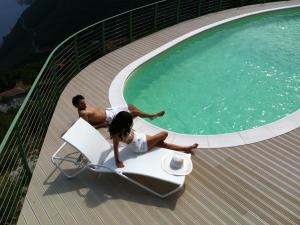 a man and a woman sitting on a chair next to a swimming pool at EnjoyIseoLake - Modigliani in Parzanica