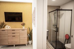 a bathroom with a shower and a television on a wall at ALMOHADES del JERTE in Galisteo +21 photos