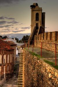 a building with a clock tower behind a stone wall at ALMOHADES del JERTE in Galisteo