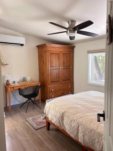 a bedroom with a bed and a desk and a ceiling fan at Hikari-Okanagan Sunshine B&B in Kelowna