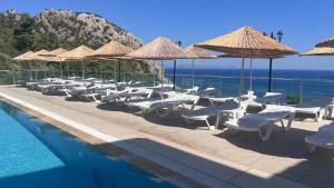 a group of chairs and umbrellas next to a swimming pool at Mavinin ve Yeşilin dansı, Panoramik manzara, 75m2 in Marmaris