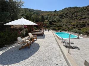 a swimming pool with chairs and an umbrella next to a pool at Finca RustiQ in Torrox