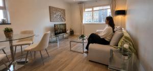 a woman sitting on a couch in a living room at Cozy 2BR apartment in Maidenhead Sleeps 6 in Maidenhead