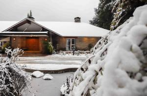 ein schneebedecktes Haus davor in der Unterkunft La Cascada Casa Patagónica by DON in San Carlos de Bariloche