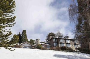 ein großes Haus auf einem schneebedeckten Hügel in der Unterkunft La Cascada Casa Patagónica by DON in San Carlos de Bariloche
