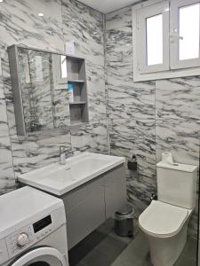a bathroom with a sink and a washing machine at Teta's Holiday Home in Melíkia