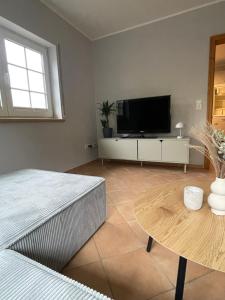 a living room with a flat screen tv and a table at Ferienwohnung Haus Liane in Reil