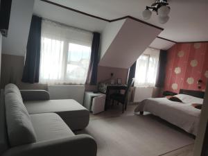 a living room with a couch and a bed and windows at Siesta Pension in Miercurea-Ciuc