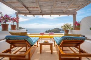 a patio with chairs and a table and a view of the ocean at Casitas in Careyes in Careyes