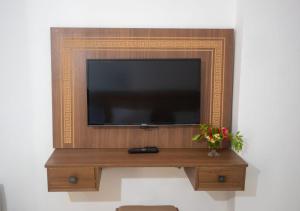 a flat screen tv on a wooden stand with a vase of flowers at Hotel Ksar Eljem in El Jem