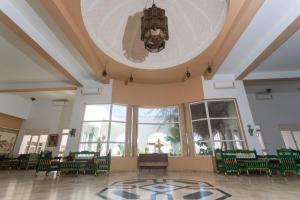 a large room with green chairs and a chandelier at Hotel Ksar Eljem in El Jem