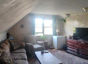 a living room with a couch and a tv at Magical stone cottage in Pine Grove Mills