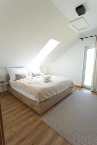 a white bedroom with a bed with a window at Malé Lipno 1075 in Černá v Pošumaví