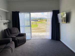 a living room with a chair and a sliding glass door at The Jam Shed in Waimate
