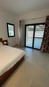 a bedroom with a bed and two large windows at Le Refuge, Residence Ibrahima in Rufisque +26 photos