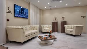 a waiting room with white chairs and a tv on a wall at Airfield Hotel & Spa in Vibo Valentia