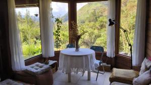 a living room with a table in front of a window at Refúgio Orquídea Bambu - Lumiar in Nova Friburgo