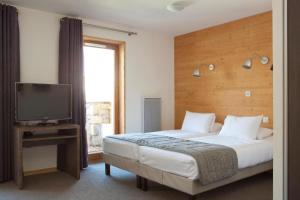 a bedroom with a large bed and a television at Alpenrose Alpe d'Huez in LʼHuez