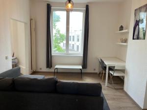 a living room with a couch and a table and a window at Cosy uccle chic flat in Brussels