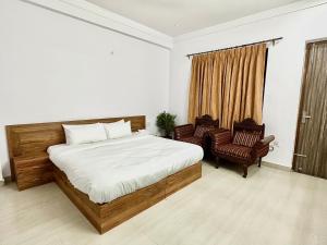 a bedroom with a large bed and two chairs at Blooming Inn in Gurgaon