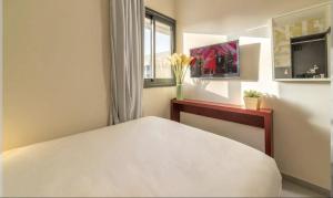 a bedroom with a white bed and a vase of flowers at HYVE Jerusalem hosted by STAY in Jerusalem
