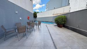 a patio with a table and chairs and a pool at Apartamento Premium com 2 quartos in Palmas