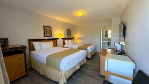 a hotel room with two beds and a television at Diplomat Motel in Nanaimo