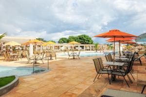 a patio with tables and chairs with umbrellas and a pool at Lacqua diRoma in Caldas Novas