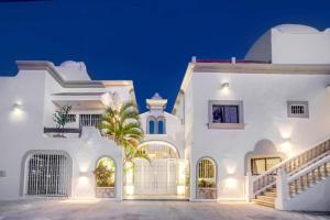 a white house with a palm tree in front of it at Valentina Suites by Las Flores Vacation Rentals in Playa del Carmen