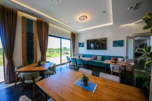 a restaurant with wooden tables and chairs and a large window at Olive Farmhouse in Hamallë