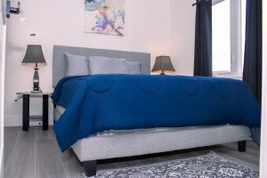 a bed with a blue blanket on it in a bedroom at Modern Private 2-Bedroom Styld, Spacious & Comfy-Modern New 2-Bedroom Stylish, Spacious, Comfy & Nicely Furnished - Full Privacy in St. John's