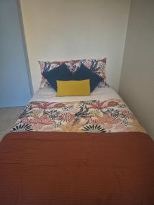 a bed with a yellow pillow on top of it at Appartement proche Le Pal 3 in Dompierre-sur-Besbre