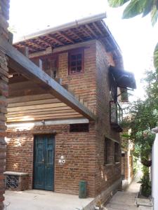 a brick building with a blue door and a balcony at Chalés na Hora in Olinda