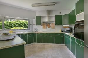 a green kitchen with green cabinets and a window at Villa 96 Golf de la Baule avec piscine et spa in Saint-André-des-Eaux