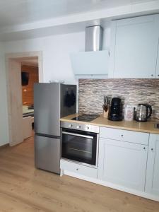 a kitchen with white cabinets and a stainless steel refrigerator at Anderer Apartment 2 in Liedolsheim