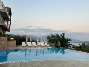 a large swimming pool with chairs and umbrellas at Acacia Hills B1 in Đenovići
