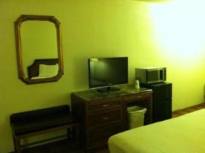 1 dormitorio con cama, TV y espejo en Waterford Inn, en Waterford