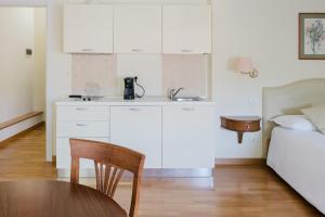 a kitchen with white cabinets and a table and a bed at Relais Villa Selle in Fumane